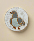 Ceramic tile with a bird design on a wooden surface
