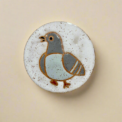 Ceramic tile with a bird design on a wooden surface