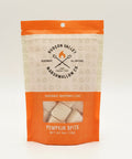 A bag of Hudson Valley Marshmallows Co. Pumpkin Spice marshmallows sits on a wooden table in a cafe setting, with a laptop and a blue-and-white striped wall visible in the background.