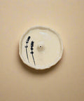 Ceramic incense holder with lavender design on a wooden surface
