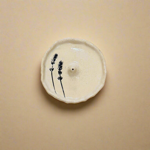 Ceramic incense holder with lavender design on a wooden surface