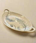 Decorative ceramic plate with leaf design on a wooden table in a store setting