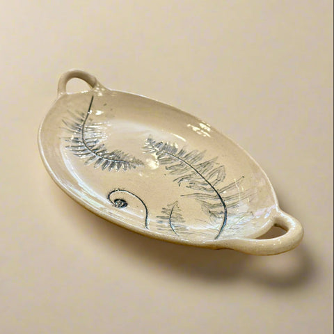 Decorative ceramic plate with leaf design on a wooden table in a store setting