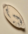 Ceramic dish with a fern design on a wooden surface