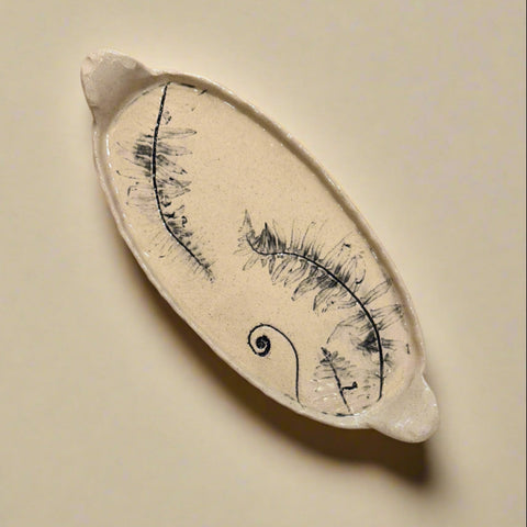 Ceramic dish with a fern design on a wooden surface
