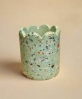 Decorative terrazzo-patterned pot on a cardboard box with a blurred background