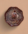 Brown ceramic incense holder with speckled pattern on a wooden surface