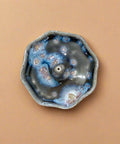 Ceramic incense holder with unique blue and gray glaze pattern on a wooden surface