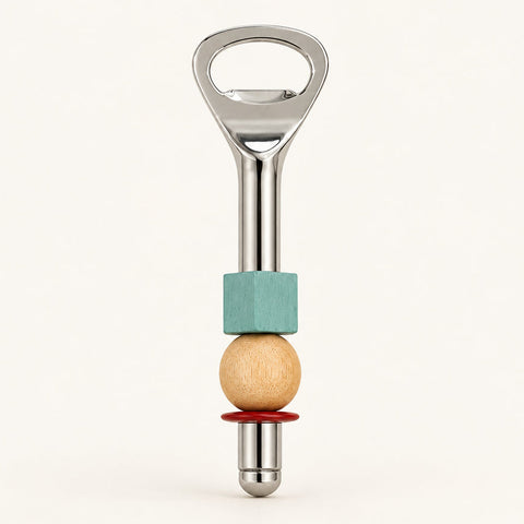 A bottle opener styled with a turquoise block, a light wood bead, and a red ring, resting on a light wood grain surface.