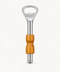 A bottle opener with a polished silver metal head and a contoured wooden handle, placed vertically on a light brown wood-grain surface.