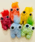 Colorful plush toys resembling monsters on a wooden surface