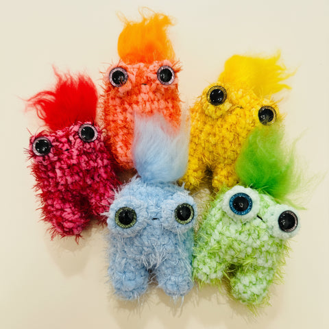 Colorful plush toys resembling monsters on a wooden surface