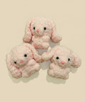 Three pink plush bunny toys on a wooden surface