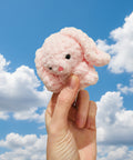 Small pink plush toy held in a hand against a neutral background