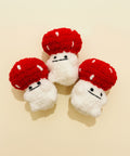 Three crochet mushrooms with red caps and white bodies on a wooden surface