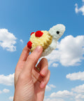 Hand holding a small crochet turtle toy against a plain background