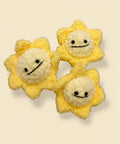 Three yellow plush toys shaped like stars with smiling faces on a wooden surface.