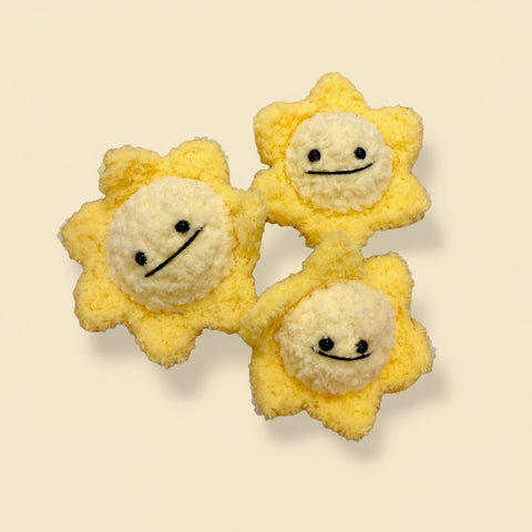 Three yellow plush toys shaped like stars with smiling faces on a wooden surface.