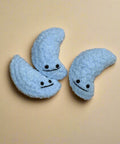 Three blue moon-shaped plush toys with faces on a wooden floor.