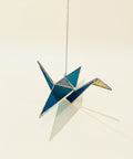 Decorative stained glass crane on a wooden surface with a store shelf in the background