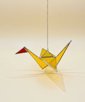 Yellow stained glass ornament on a wooden surface with a blurred background.