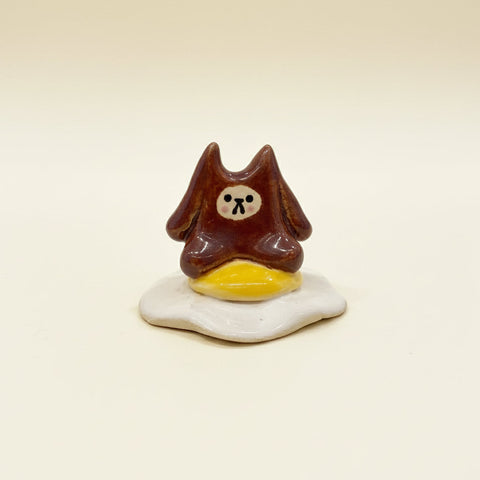 Small figurine of a brown bear on a fried egg