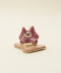 Small ceramic figure of a bear sitting on a piece of buttered toast