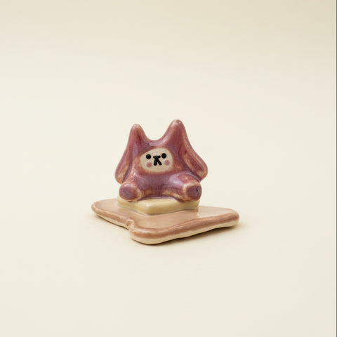 Small ceramic figure of a bear sitting on a piece of buttered toast