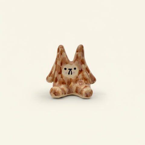 Small ceramic dog figurine on a wooden surface with a jar of lip balm in the background.