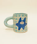 Ceramic mug with a blue star design on a wooden surface