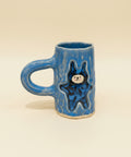 Blue ceramic mug with a bear design on a wooden surface