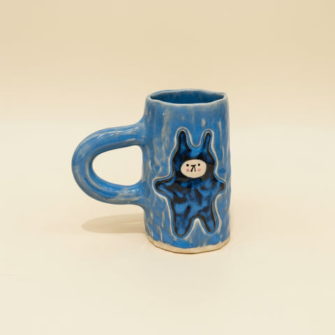 Blue ceramic mug with a bear design on a wooden surface