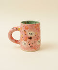 Pink ceramic mug with abstract design on a wooden surface