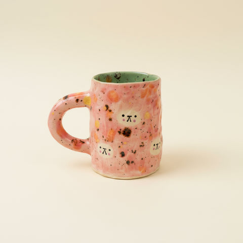 Pink ceramic mug with abstract design on a wooden surface