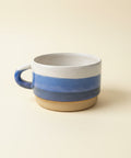 Ceramic mug with blue and beige stripes on a white surface