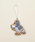 Decorative pigeon ornament holding a cup on a wooden surface