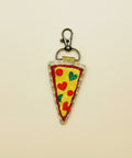 Pizza slice keychain with a clip on a wooden surface