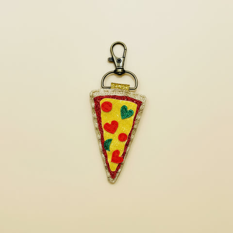 Pizza slice keychain with a clip on a wooden surface
