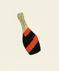 Decorative bottle-shaped object with gold top, red middle, and black bottom on a wooden surface