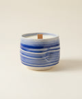 Blue and white ceramic mug with a candle on a wooden surface