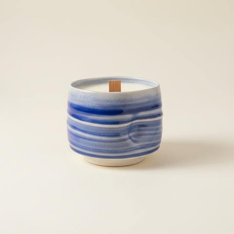 Blue and white ceramic mug with a candle on a wooden surface