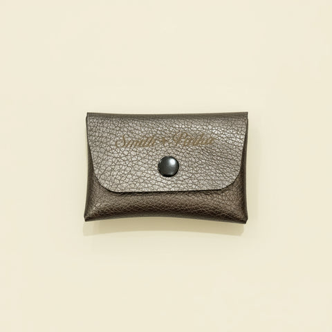 Silver textured wallet with a button on a wooden surface