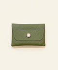 Green leather wallet with a button on a wooden surface
