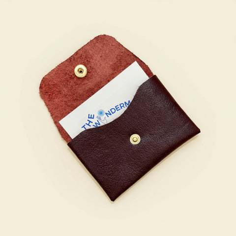 Brown leather cardholder with a white card inserted inside