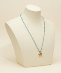 Necklace with blue beads and a gold charm on a wooden surface