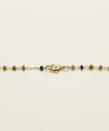Gold necklace with small beads on a wooden surface