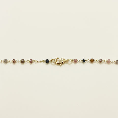 Gold necklace with small beads on a wooden surface