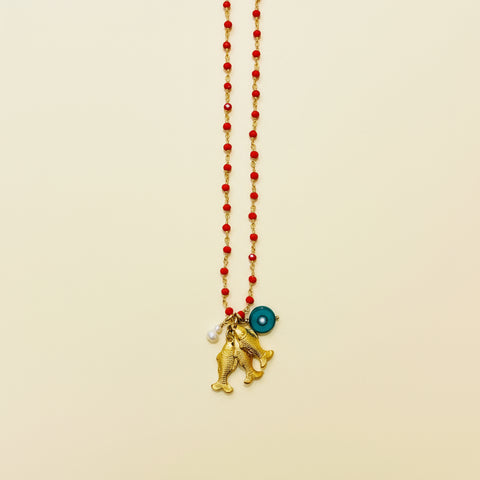 Necklace with gold pendants and red beads on a wooden surface