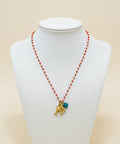 Necklace with red beads and gold charm on a wooden surface