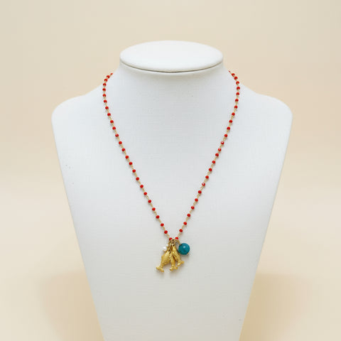 Necklace with red beads and gold charm on a wooden surface
